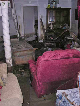 Lower 9th Ward homes after Katrina all look alike, furniture tossed, belongings piled against doorways, everything coated in thick mud 280x373